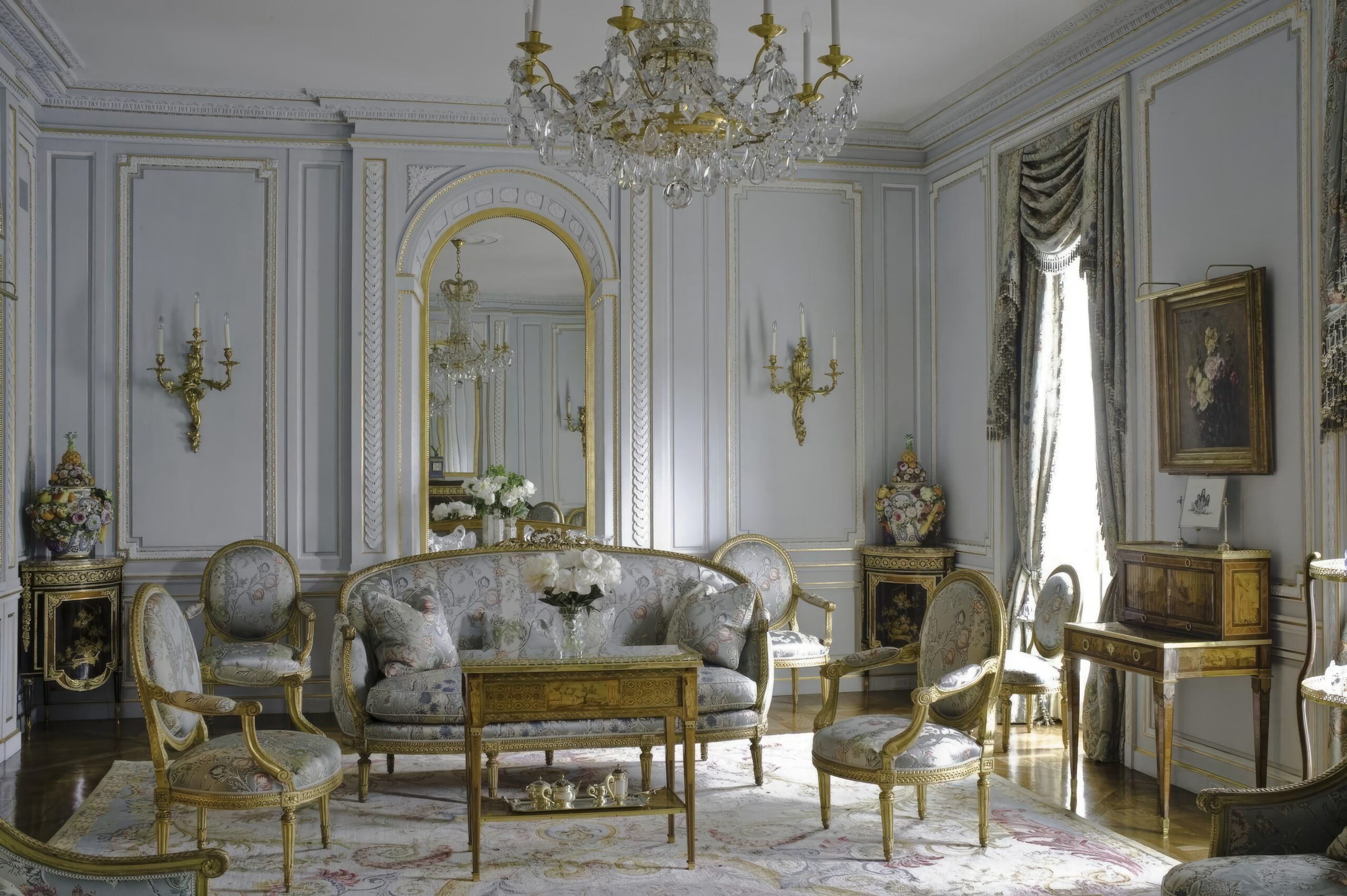 A room with a couch chairs and a chandelier